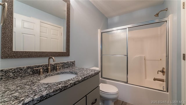 full bath featuring enclosed tub / shower combo, vanity, and toilet