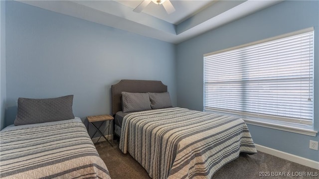 bedroom featuring carpet floors, a tray ceiling, baseboards, and a ceiling fan