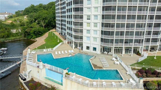 community pool with a patio area, a water view, and a fenced backyard