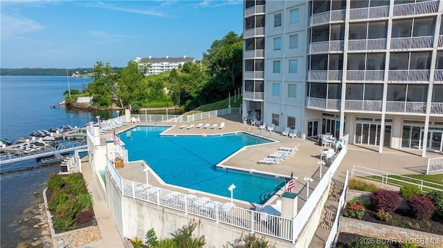 community pool featuring a water view, fence, and a patio