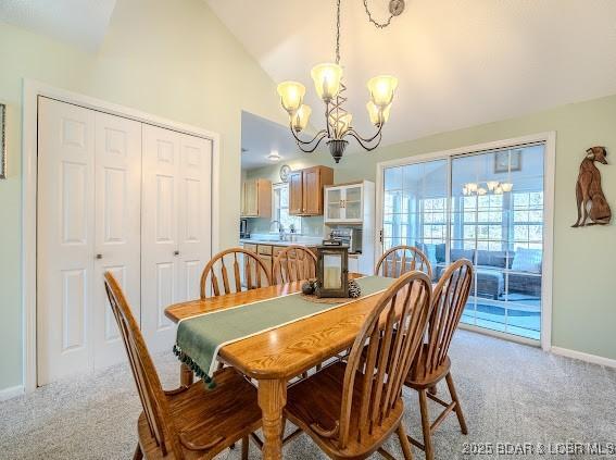 dining area with vaulted ceiling, light carpet, a notable chandelier, and baseboards