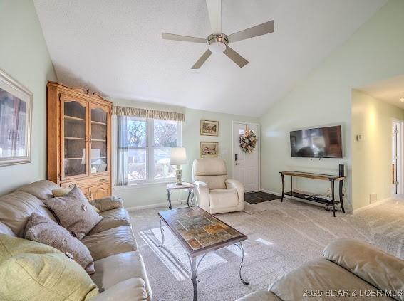 living area with high vaulted ceiling, light colored carpet, ceiling fan, and baseboards