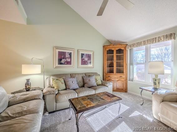 living area featuring a textured ceiling, high vaulted ceiling, ceiling fan, light carpet, and baseboards