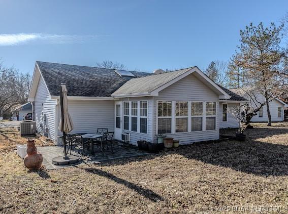 back of property with a patio, roof with shingles, and central air condition unit