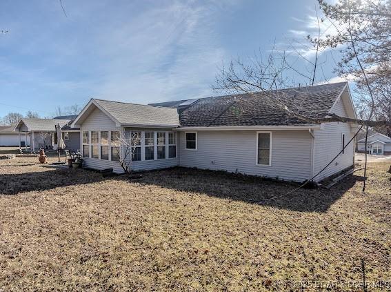 back of house with a sunroom and a lawn