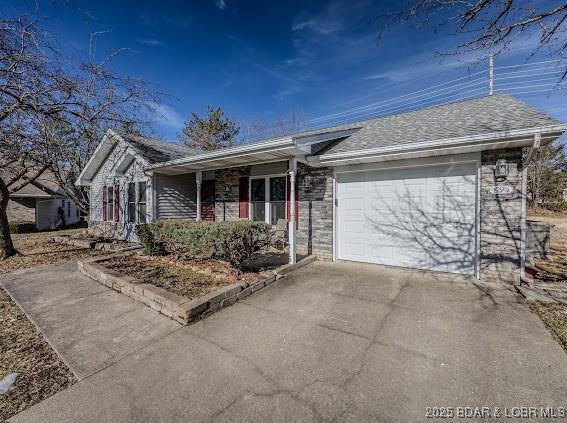 ranch-style house featuring concrete driveway, roof with shingles, and an attached garage