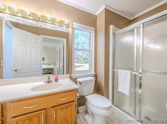 full bathroom with toilet, a shower stall, a textured ceiling, and vanity