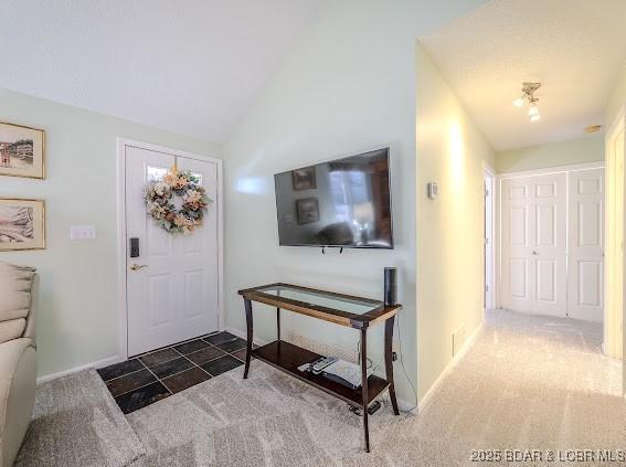 carpeted foyer entrance featuring vaulted ceiling and baseboards