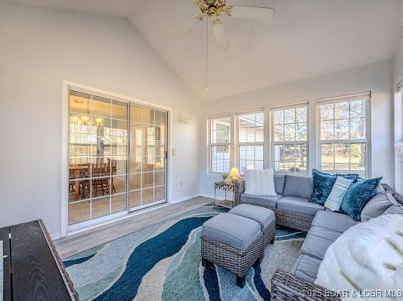 living area with a ceiling fan, lofted ceiling, baseboards, and wood finished floors