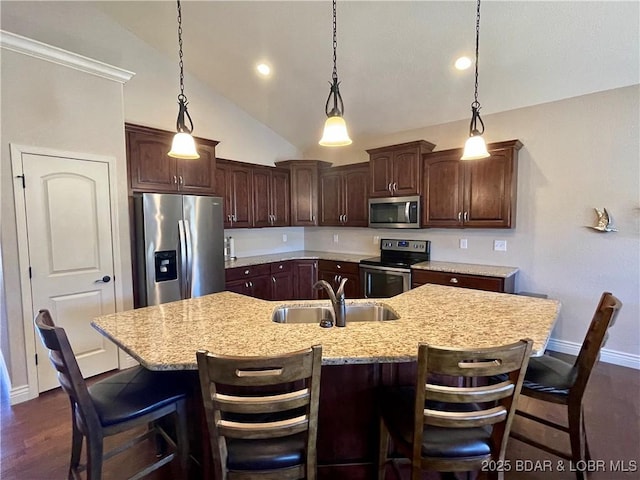 kitchen with dark wood finished floors, appliances with stainless steel finishes, a kitchen island with sink, a sink, and dark brown cabinets