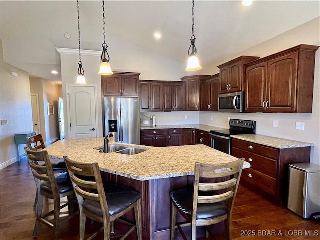 kitchen featuring stainless steel appliances, dark wood-style flooring, a sink, an island with sink, and a kitchen bar