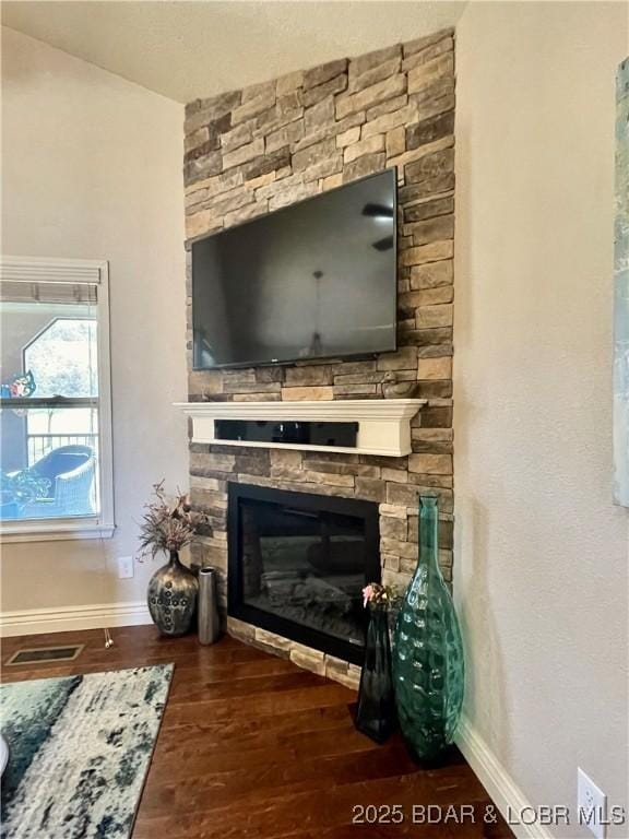 room details featuring a fireplace, wood finished floors, visible vents, and baseboards