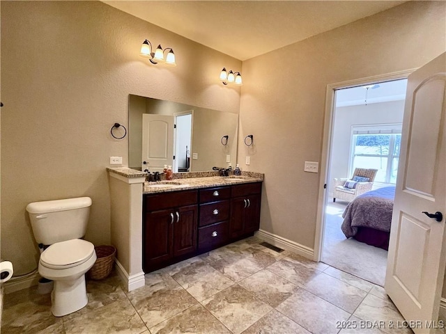 ensuite bathroom featuring ensuite bathroom, a sink, baseboards, and double vanity