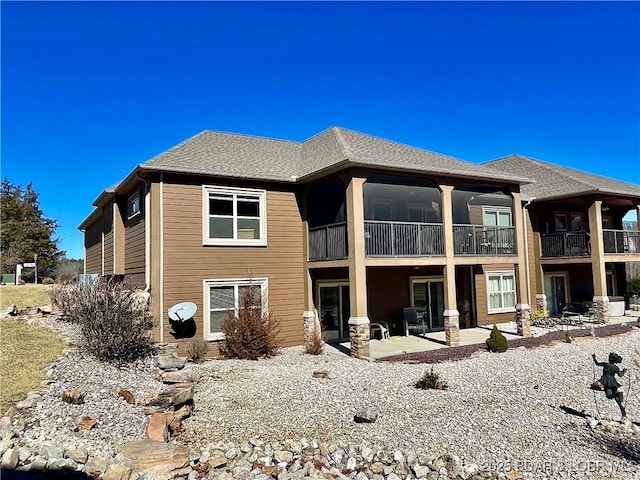 rear view of property featuring roof with shingles and a patio area