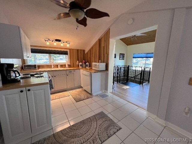 kitchen with light tile patterned floors, white appliances, a sink, a ceiling fan, and vaulted ceiling