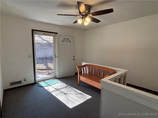 interior space with baseboards, visible vents, dark carpet, and a ceiling fan