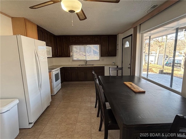 kitchen featuring light countertops, light tile patterned flooring, a sink, a textured ceiling, and white appliances