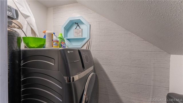 details featuring a textured ceiling, wood walls, and washing machine and dryer