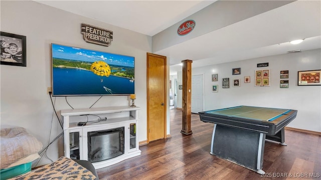 playroom with baseboards, a glass covered fireplace, wood finished floors, and ornate columns