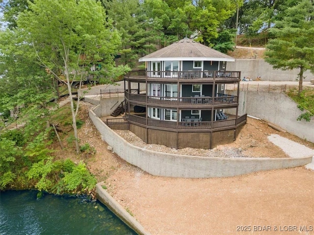 back of house with a deck with water view and stairs