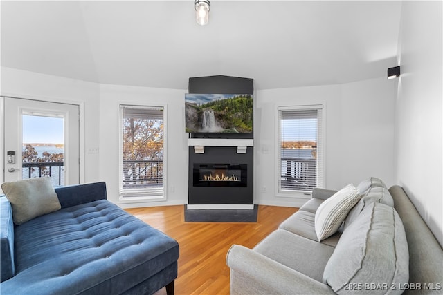 living area with lofted ceiling, light wood-style floors, and a glass covered fireplace