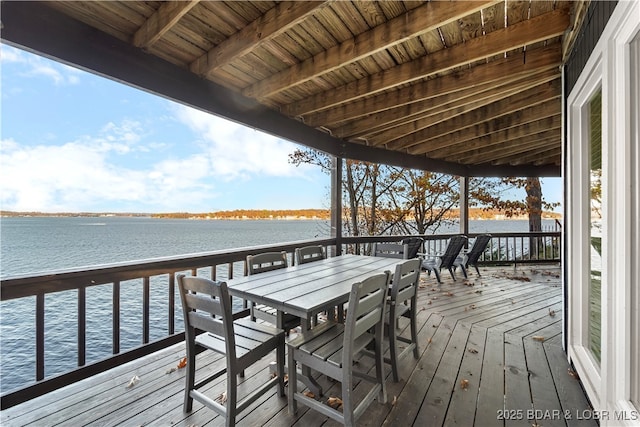 wooden deck with a water view and outdoor dining area