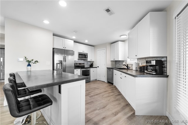 kitchen featuring stainless steel appliances, dark countertops, visible vents, and white cabinets