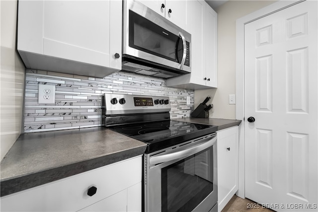kitchen with tasteful backsplash, appliances with stainless steel finishes, dark countertops, and white cabinets