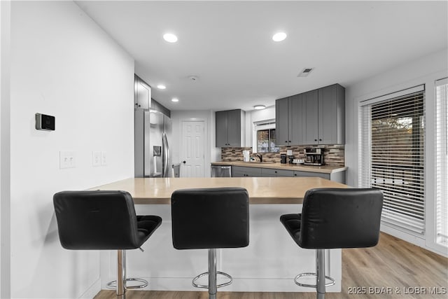 kitchen featuring a peninsula, tasteful backsplash, appliances with stainless steel finishes, and light countertops