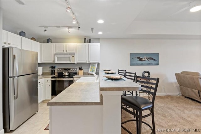 kitchen featuring stainless steel appliances, a breakfast bar, a peninsula, white cabinets, and recessed lighting