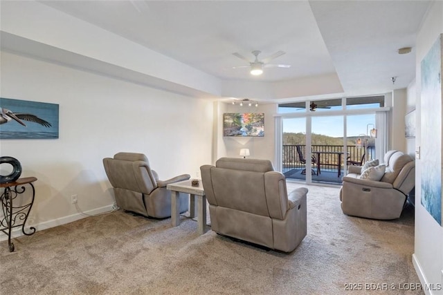 living room featuring carpet flooring, a ceiling fan, baseboards, and a tray ceiling