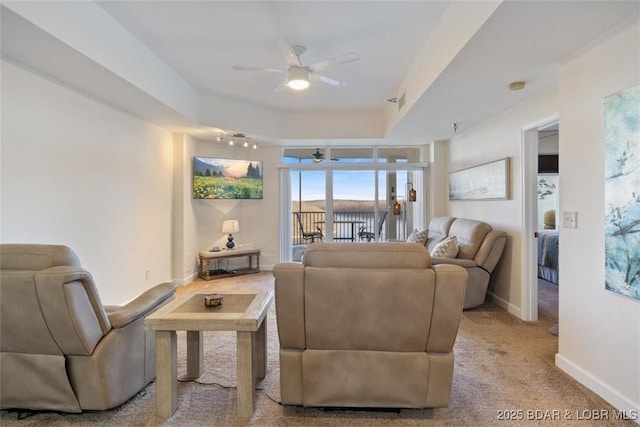 carpeted living area featuring ceiling fan and baseboards