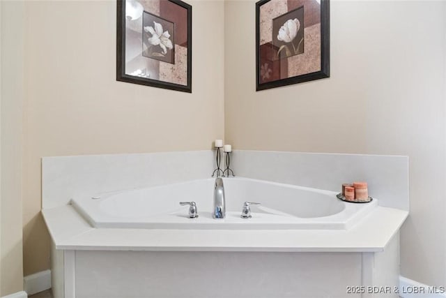 bathroom with a bath and baseboards