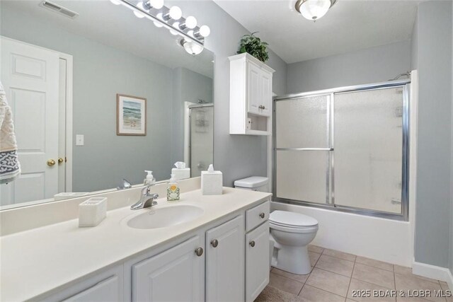 bathroom featuring tile patterned floors, vanity, toilet, and shower / bath combination with glass door