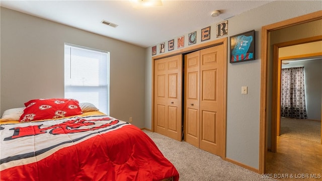 carpeted bedroom with a closet, visible vents, and baseboards