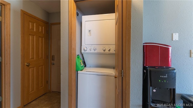 washroom with stacked washer and clothes dryer, a textured wall, and laundry area