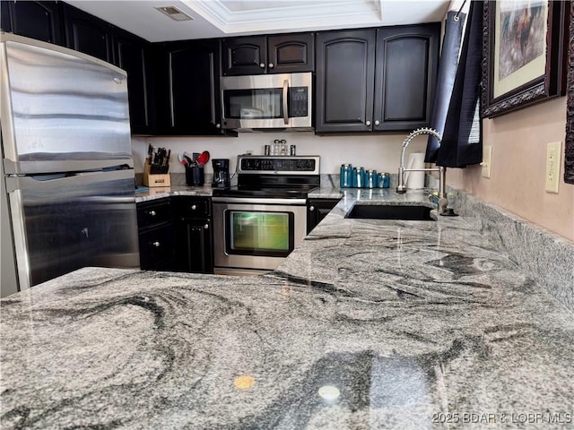 kitchen with appliances with stainless steel finishes, visible vents, a sink, and light stone counters