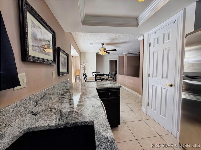 kitchen with light tile patterned floors, ornamental molding, ceiling fan, a textured ceiling, and a peninsula