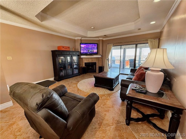 living room featuring a textured ceiling, a tile fireplace, and a raised ceiling