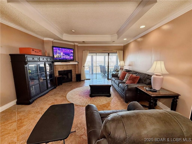 tiled living room with a raised ceiling, ornamental molding, a textured ceiling, a tile fireplace, and baseboards