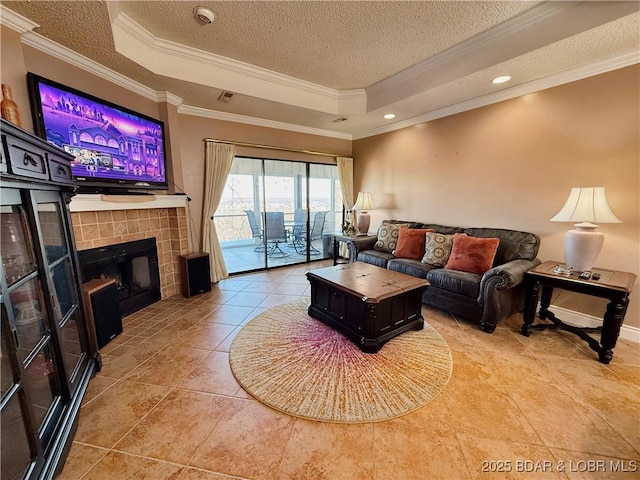 tiled living area featuring a tray ceiling, crown molding, visible vents, a textured ceiling, and a tile fireplace