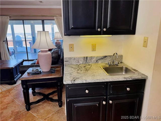 kitchen with crown molding, light tile patterned floors, a sink, and dark cabinets