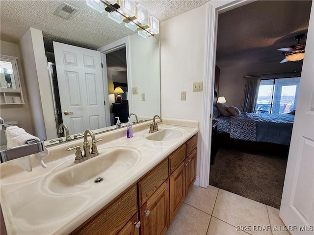 ensuite bathroom featuring tile patterned flooring, a sink, a textured ceiling, and ensuite bathroom