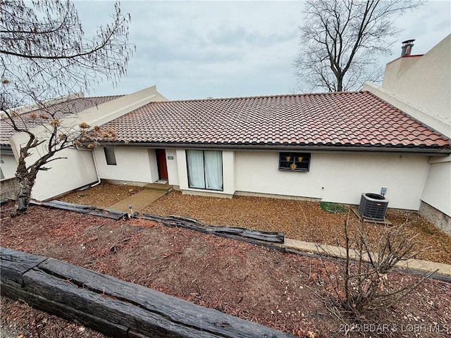 rear view of property with central air condition unit, a tiled roof, and stucco siding