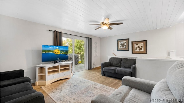 living room with a ceiling fan, baseboards, and wood finished floors