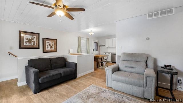 living area featuring baseboards, visible vents, ceiling fan, and light wood finished floors