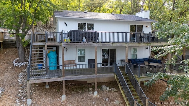 rear view of house featuring a deck, a chimney, stairway, and an outdoor hangout area