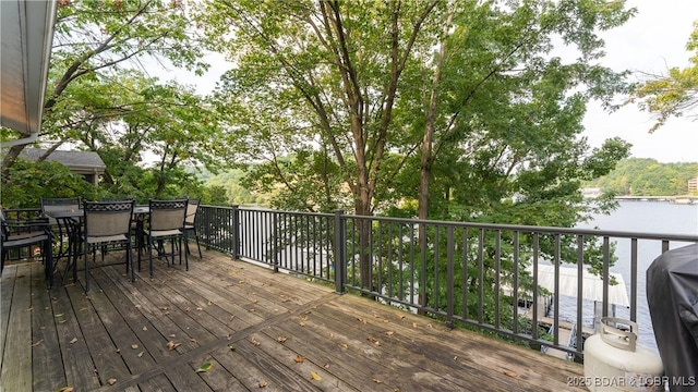 deck with outdoor dining area and a water view