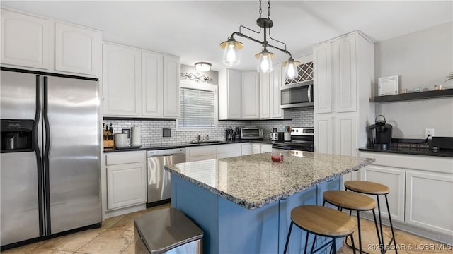 kitchen with a sink, stainless steel appliances, white cabinetry, a kitchen breakfast bar, and tasteful backsplash