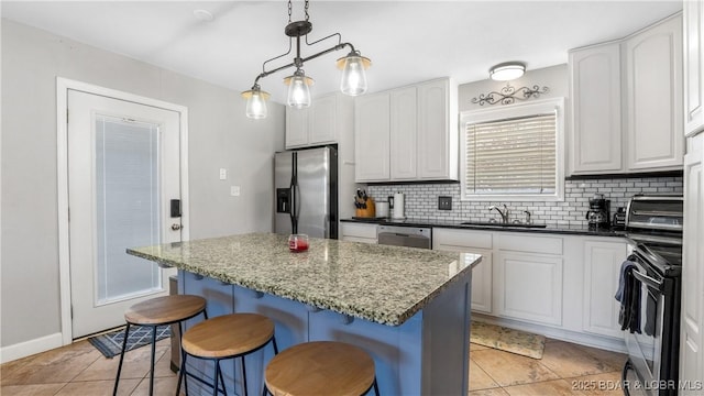 kitchen featuring a breakfast bar area, a sink, white cabinets, appliances with stainless steel finishes, and tasteful backsplash